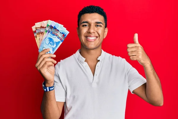 Hombre Árabe Joven Sosteniendo Dólares Canadienses Sonriendo Feliz Positivo Pulgar —  Fotos de Stock