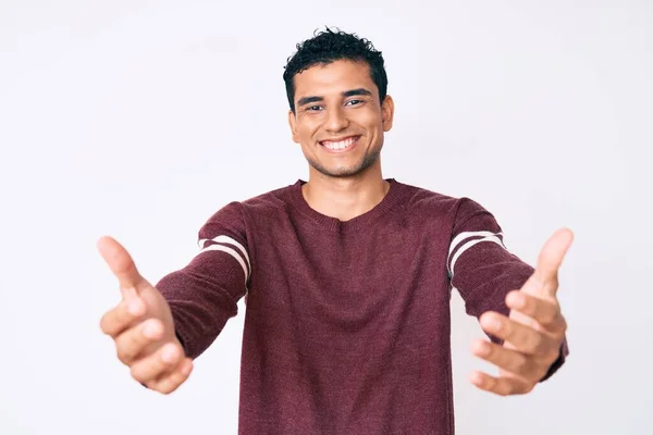 白い背景の上に若いハンサムなヒスパニック系の男は カメラを見て抱擁のために腕を開いて笑顔 幸せを受け入れる陽気な表情 — ストック写真