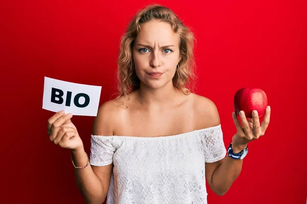 Krásná Běloška Drží Červené Jablko Bio Slovo Skeptické Nervózní Mračí — Stock fotografie