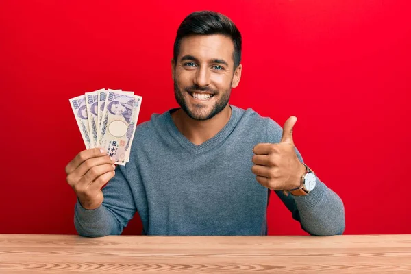 Hombre Hispano Guapo Sosteniendo Billetes Yen Japoneses Sonriendo Feliz Positivo — Foto de Stock