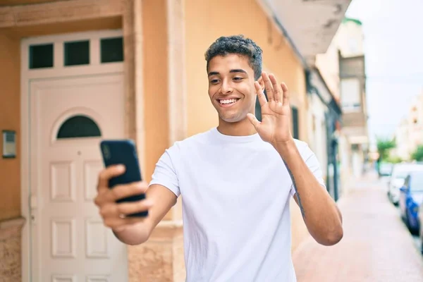 若いラテン語の男の笑顔幸せな行うビデオ通話を使用してスマートフォンで市内 — ストック写真