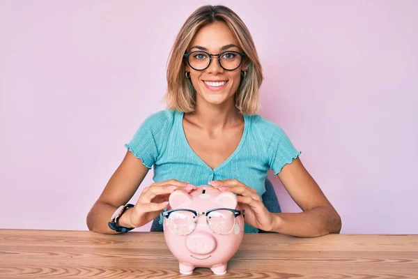 Mooie Kaukasische Vrouw Houden Spaarvarken Bank Met Bril Kijken Positief — Stockfoto