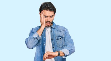 Gündelik giysiler giyen genç İspanyol adam saate bakıyor. Endişeli, geç kalmaktan korkuyor. 