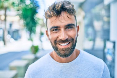 Genç İspanyol adam gülümseyerek şehirde mutlu bir şekilde yürüyor.