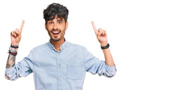 Gündelik kıyafetler giyen genç İspanyol adam şaşırmış, şaşırmış ve parmaklarıyla işaret ediyor ve kollarını kaldırıyordu.. 