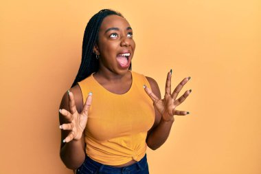 Genç Afro-Amerikalı kadın gündelik kıyafetler giyip deli gibi bağırıyor, agresif bir ifadeyle bağırıyor ve kollarını kaldırıyor. hüsran kavramı. 