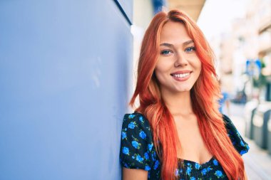 Genç kızıl saçlı kız gülümsüyor Mutlu bir şekilde yürüyor şehrin caddesinde.