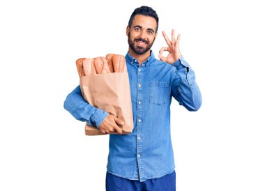 Elinde ekmek olan genç İspanyol adam. Parmaklarıyla imza atıyor. Gülümsüyor. 