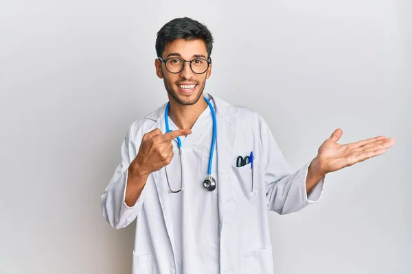 Młody Przystojny Mężczyzna Mundurze Lekarza Stetoskopie Zdumiony Uśmiechnięty Aparatu Prezentujący — Zdjęcie stockowe