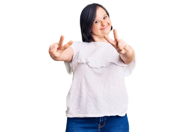 布鲁内特女患者身穿休闲的白色T恤 带着舌头微笑 伸出双手的手指做胜利的手势 第二点 — 图库照片