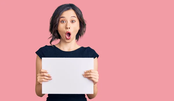 Menina Bonita Jovem Segurando Banner Vazio Branco Assustado Espantado Com — Fotografia de Stock