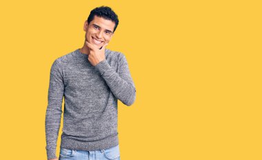 İspanyol asıllı yakışıklı, sıradan bir süveter giyen, kameraya kendinden emin, kolları çapraz ve çenesi havada gülümseyen genç bir adam. Olumlu düşünmek. 