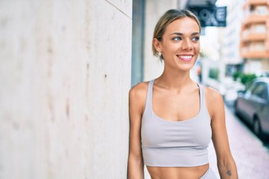 Beyaz tenli spor elbiseli kadın açık havada antrenman yapıyor.