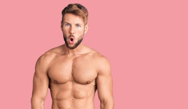 Genç, beyaz bir adam tişörtsüz duruyor. Korkmuş ve şok olmuş bir halde.. 