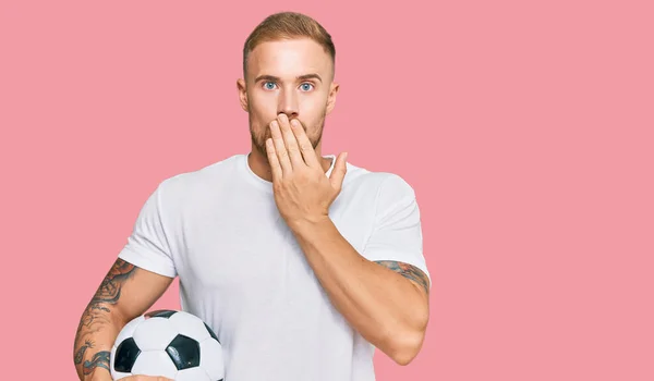 手で口を覆うサッカーボールを持っている若いアイルランドの男はショックを受け 間違いを恐れている 驚きの表情 — ストック写真