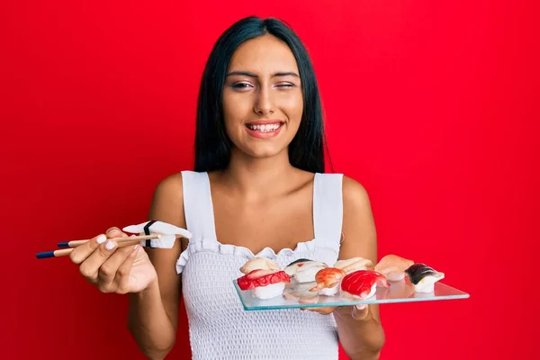 Jovem Morena Comendo Sushi Morango Usando Pauzinhos Piscando Olhando Para — Fotografia de Stock