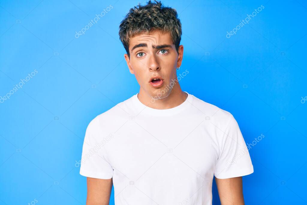 Young handsome man wearing casual white t shirt scared and amazed with open mouth for surprise, disbelief face 