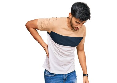 Sırt ağrısından muzdarip sıradan kıyafetler giyen genç yakışıklı bir adam, elleriyle dokunuyor, kas ağrısı çekiyor. 