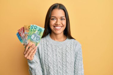 Güzel İspanyol kadın elinde dolarlarla pozitif ve mutlu görünüyor. Kendine güvenen bir gülümsemeyle dişlerini gösteriyor. 