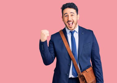 İspanyol takım elbiseli ve deri çantalı genç adam gururla bağırıyor zaferi kutluyor ve başarıyı kollarını kaldırarak kutluyor. 