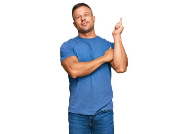 Yakışıklı, sıradan kıyafetler giyen, yüzünde kocaman bir gülümseme olan, eli ve parmağı kameraya bakan kaslı bir adam.. 