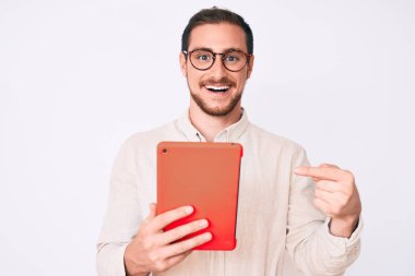 Genç yakışıklı adam dokunmatik bir cihaz kullanıyor. Gülümsüyor, mutlu bir şekilde işaret ediyor. 