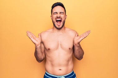 Sarı arka planda kolsuz tişört giyen sakallı yakışıklı genç adam kollarını kaldırmış ve gözleri kapalı heyecanla haykırarak başarıyı kutluyor. Kazanan konsept