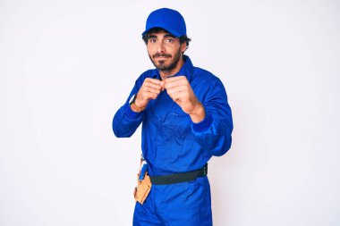 Kıvırcık saçlı ve ayı gibi giyinmiş yakışıklı bir genç adam. Yumruk savunma hareketleriyle dövüşmeye hazır. Kızgın ve üzgün. 