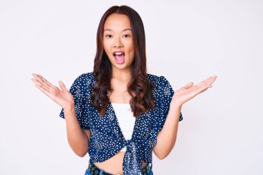 Genç, güzel Çinli kız gündelik giysiler içinde zaferi mutlu bir gülümsemeyle kutluyor ve kazanan yüz ifadesi kaldırıyor. 