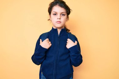 Sırt çantası tutan tatlı İspanyol çocuk. Düşünme tavrı ve ayık yüz ifadesi. Kendinden emin görünüyor. 