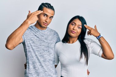 Gündelik giysiler giymiş genç Latin bir çift silah gibi el ve parmakları işaret ederek kendini vuruyor, intihar ediyor.. 