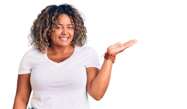 Genç Afro-Amerikan artı cüsseli kadın günlük kıyafetler giyiyor neşeli bir şekilde gülümsüyor ve avuç içi kameraya bakıyor.. 