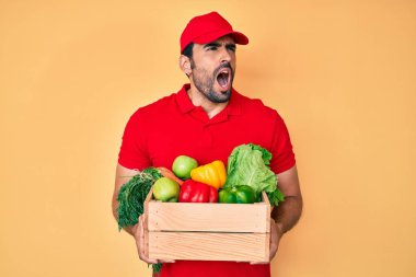 Yakışıklı, sakallı, üniformalı, elinde yiyecek, kızgın ve kızgın çığlıklar atan sinirli, öfkeyle bağıran bir adam. öfke ve agresif konsept. 