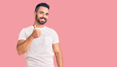 Gündelik kıyafetler giyen genç İspanyol adam elleriyle mutlu bir jest yapıyor. Kameraya bakıp başarıyı gösteren ifade. 