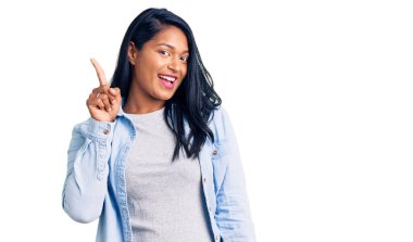 Uzun saçlı İspanyol kadın rahat kot ceket giyiyor. Bir numarayı işaret ediyor ve gülümsüyor. Kendinden emin ve mutlu.. 