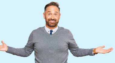 İş elbiseleri giymiş yakışıklı orta yaşlı bir adam gülümseyerek avuçlarını açıyor, sunuyor ve reklam karşılaştırması yapıyor ve dengeyi sağlıyor. 