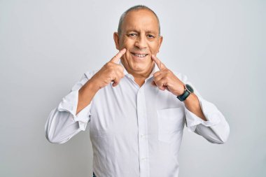 Yakışıklı, beyaz gömlekli, ağzı açık gülümseyen, parmakları işaret eden ve neşeli gülümsemeye zorlayan bir adam. 