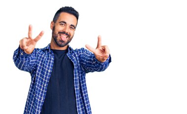 Gündelik giysiler giymiş, ağzı açık gülümseyen genç İspanyol adam zafer işareti yaparken parmaklarını gösteriyor. İki numara.. 