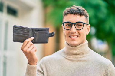 Genç İspanyol adam gülümseyerek şehirde mutlu mesut dikiliyor..