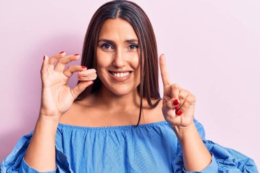 Genç ve güzel esmer bir kadın elinde bir fikirle gülümseyen ya da mutlu bir yüzle parmağını gösteren bir makaron tutuyor. 