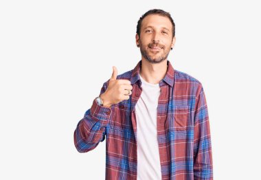 Gündelik giysiler giyen genç yakışıklı adam elleriyle mutlu bir jest yapıyor. Kameraya bakıp başarıyı gösteren ifade. 