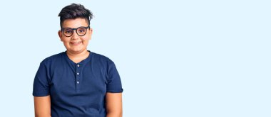 Yüzünde mutlu ve havalı bir gülümseme olan günlük kıyafetler ve gözlük takan küçük bir çocuk. şanslı kişi. 