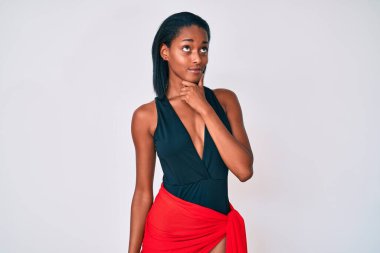 Elleri çenesinde mayo giymiş, soru soran genç Afro-Amerikan kadın, düşünceli bir ifade. Düşünceli bir yüzle gülümsüyor. şüphe kavramı. 