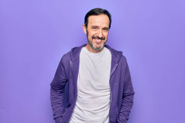 Yüzünde mutlu ve havalı bir gülümseme ile izole bir arka plan üzerine sıradan mor bir kazak giyen orta yaşlı yakışıklı bir sporcu. Şanslı kişi..