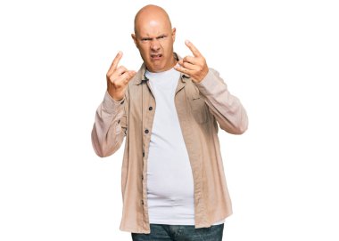 Orta yaşlı kel bir adam, günlük giysiler içinde çılgın bir ifadeyle bağırıyor ve elleri havada rock sembolü yapıyor. Müzik yıldızı. ağır kavram. 