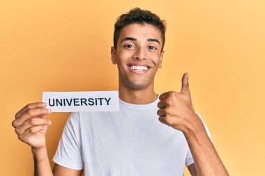 Üniversite sözcüğüyle gülümseyen, mutlu ve olumlu gülümseyen, mükemmel ve onay işareti yapan genç, Afro-Amerikalı bir adam. 