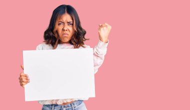 Genç, güzel, melez bir kadın elinde boş alanı olan karton bir pankart tutuyor öfkeyle bağırıyor, öfkeyle bağırıyor ve el kaldırıyor. 