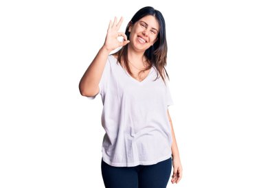 Genç, güzel, esmer, günlük tişört giyen, gülümseyen, el ve parmaklarıyla 