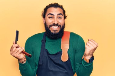 Önlük giymiş genç Arap adam berber jileti tutuyor gururla bağırıyor, zaferi kutluyor ve başarıyı kollarını kaldırarak kutluyor. 