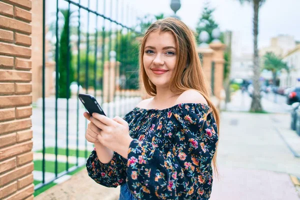 若い赤毛の女性は 街の通りを歩くスマートフォンを使用して幸せな笑顔 — ストック写真